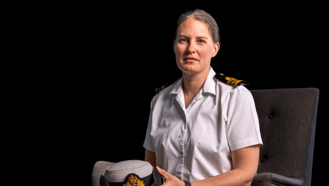 Woman sat looking at the camera in Naval uniform. 