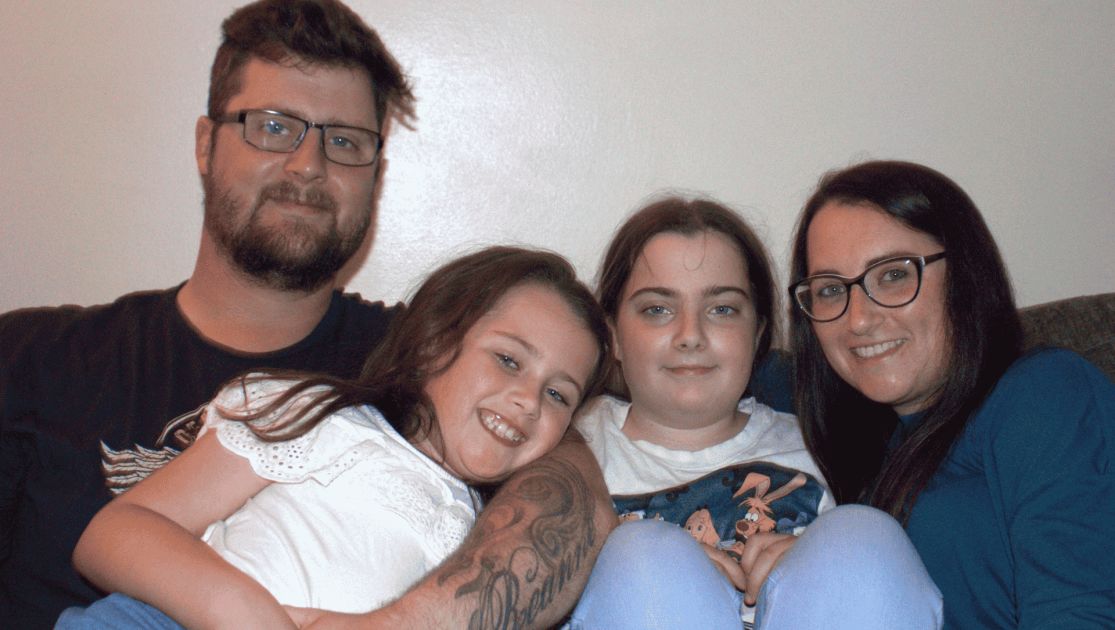 Family sat together smiling looking at the camera