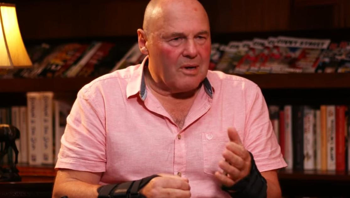 Man sat in a pink shirt looking away from camera