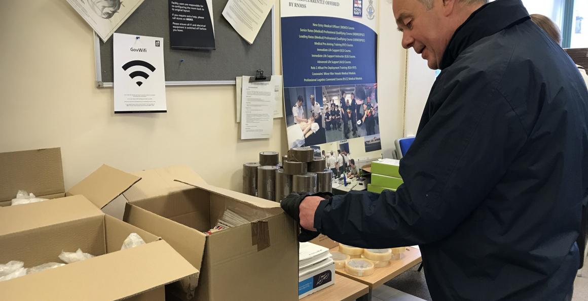 RNRMC CEO Adrian Bell helping pack boxes for distribution at the Institute of Naval Medicine