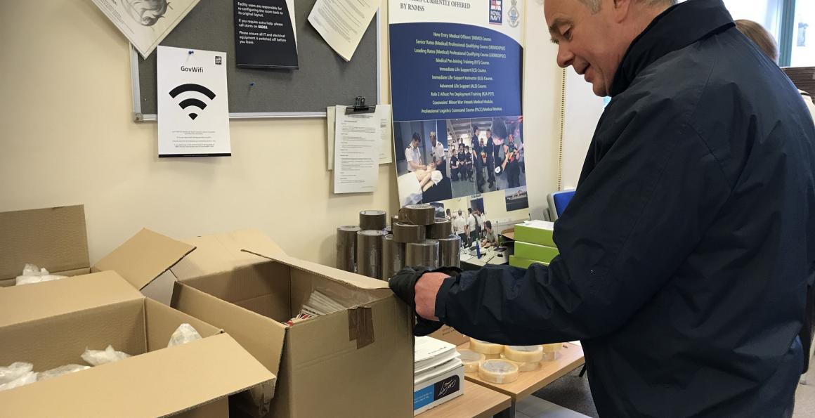 RNRMC CEO Adrian Bell helping pack boxes for distribution at the Institute of Naval Medicine