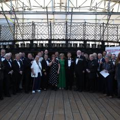 Group shot of peopel in formal attire onbaord the deck of the HMS Victory