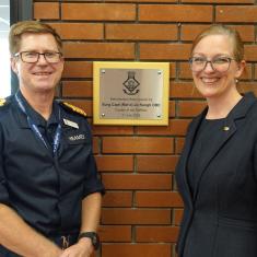 Two peopel stood in front of a plaque