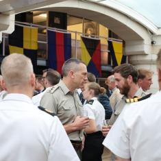 people networking and talking, wearing naval uniform