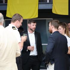 people networking and talking, wearing naval uniform