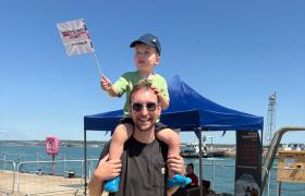 Man with child sat on his shoulders waving a flag