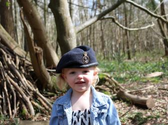 Small child wearing a Naval cap, stood in the woods