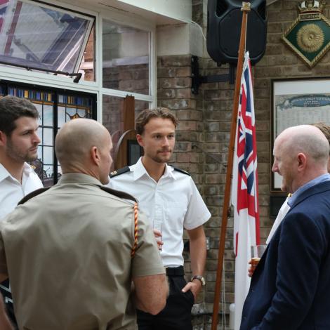 people networking and talking, wearing naval uniform