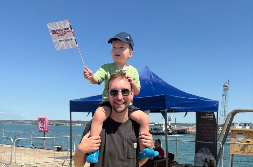 Man with child sat on his shoulders waving a flag