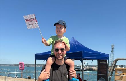 Man with child sat on his shoulders waving a flag