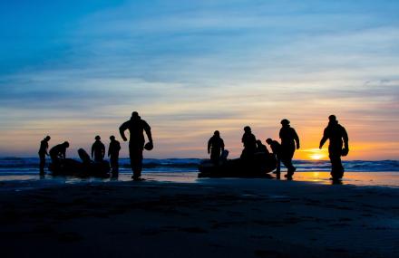 Royal Marines at sunset on the beach coming out of the surf.