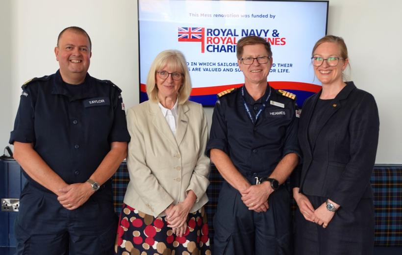 four people stood in front of a screen with RNRMC details on it