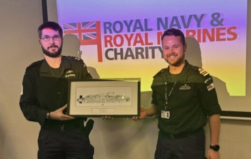 Two men standing infront of an RMRNC screen - one is holding a picture of a boat. Both are smiling at the camera.